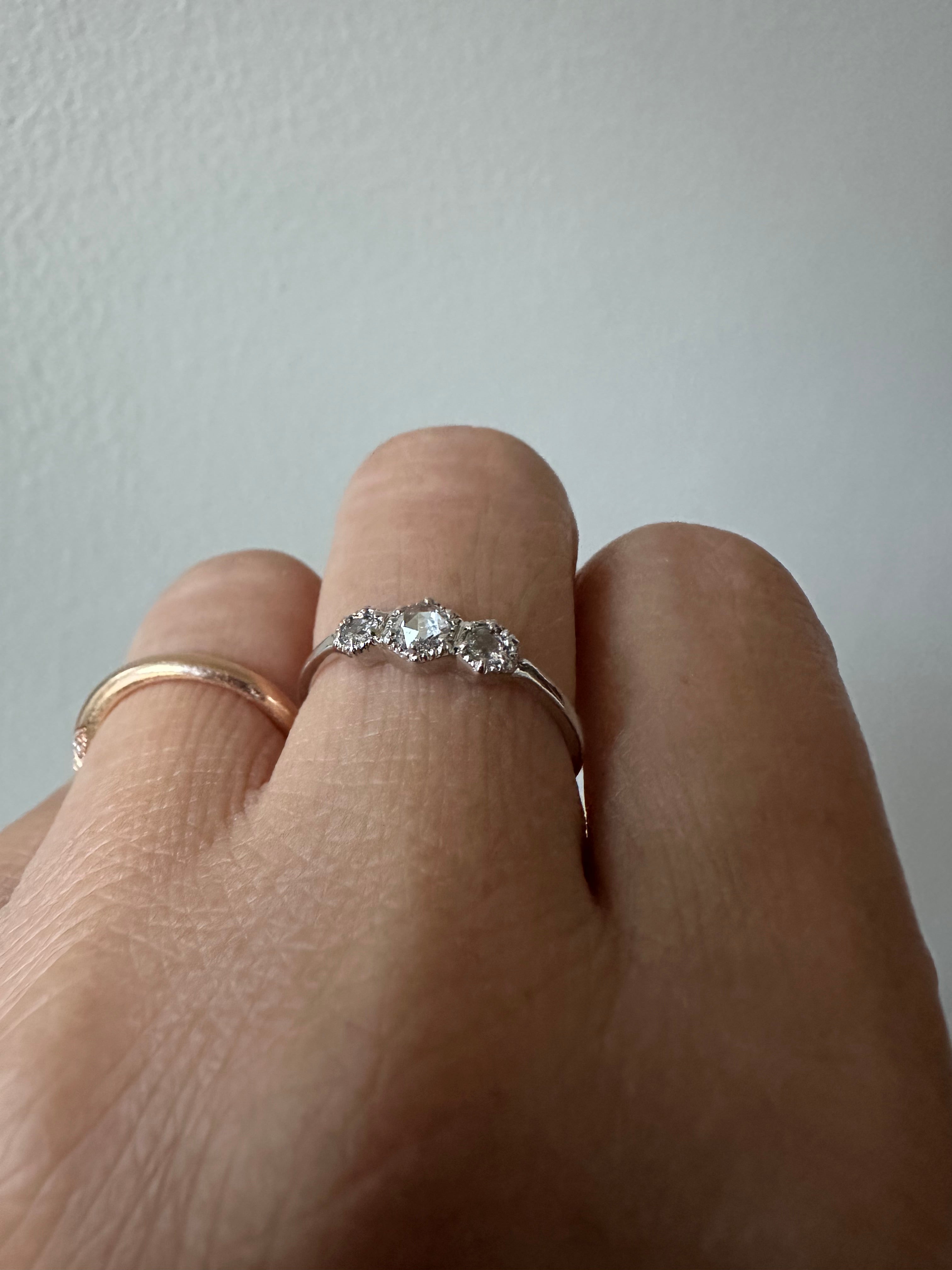 Close-up of a hand wearing a diamond ring on a neutral background